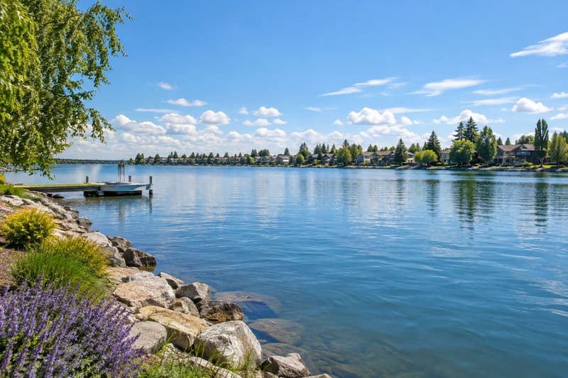 Chestermere Lake at dusk, boats moored along the shore and the Calgary skyline low on the horizon.